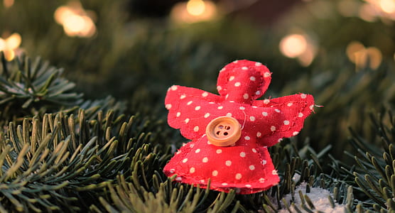 angel-shaped red and white polka-dot ornament on green surface