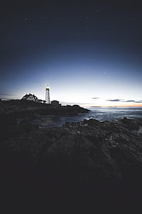 white lighthouse near body of water under starry sky