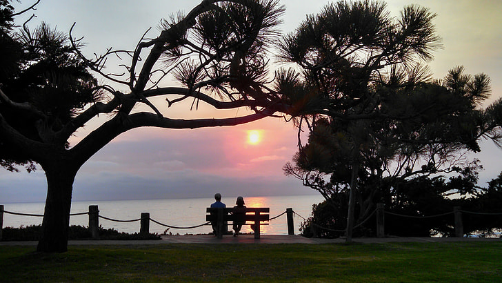 silhouette of couple sitting on bench