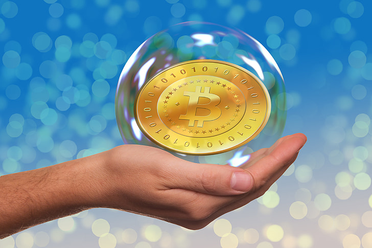 person's left hand holding bubble with Bitcoin inside
