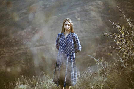 woman wearing blue and white long-sleeved dress standing on green grass
