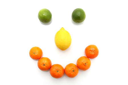 orange fruits and lemon formed smiley on white surface