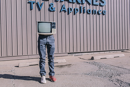 CRT television on person wearing gray denim jeans and white and red sneakers