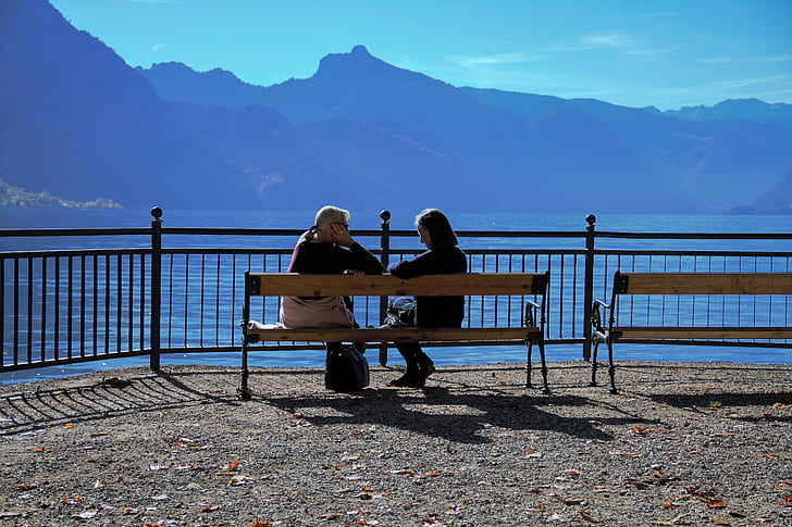women seating on brown wooden bench