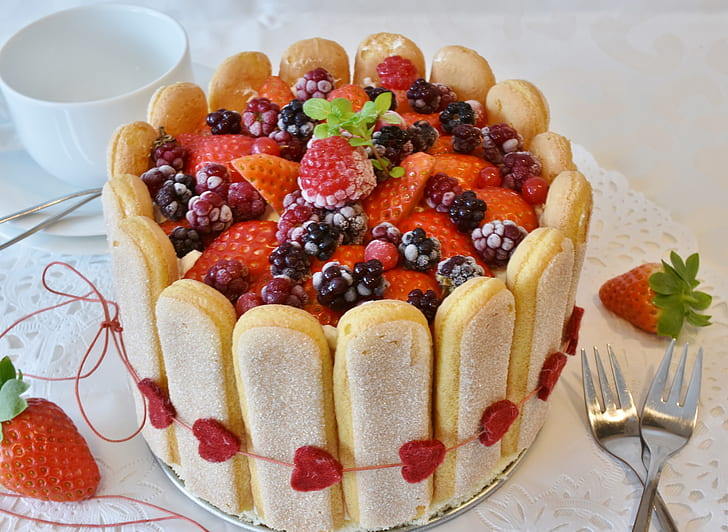 round strawberry cake beside two table forks