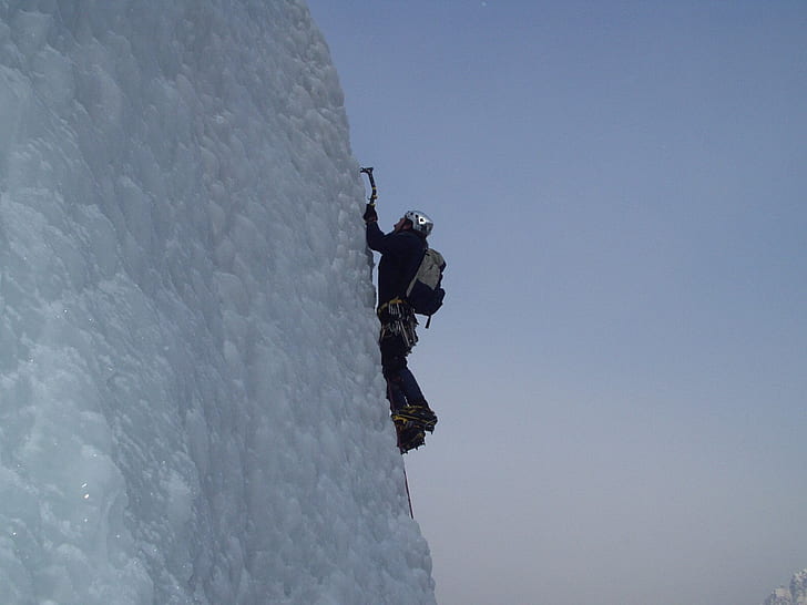 man climbing a snow covered mountain