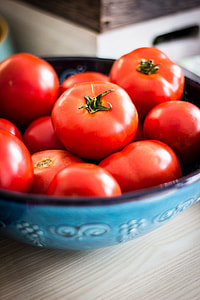 tomatoes in blue ceramic bowl on wooden table