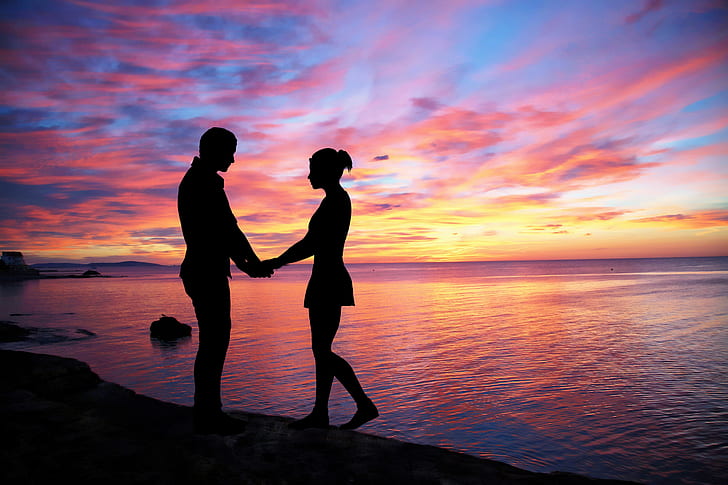 silhouette of man and woman near body of water
