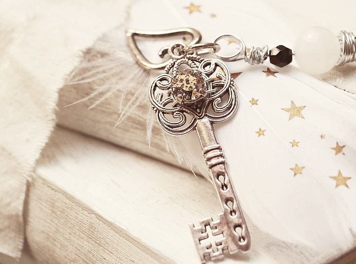 silver-colored skeleton key pendant on white textile