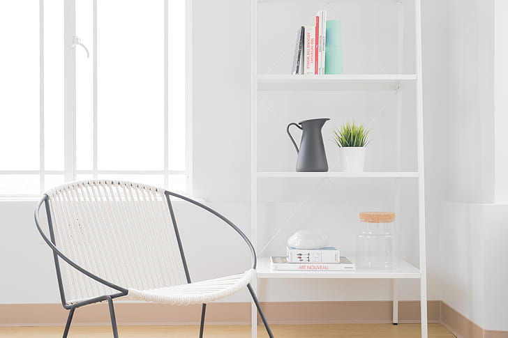 white armchair with gray steel frame near white wooden 3-layer shelf