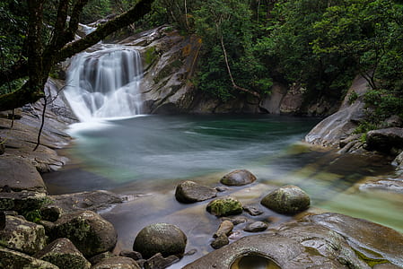 time-lapse photography of waterfalls surrounded with gray rocks and green trees during daytime
