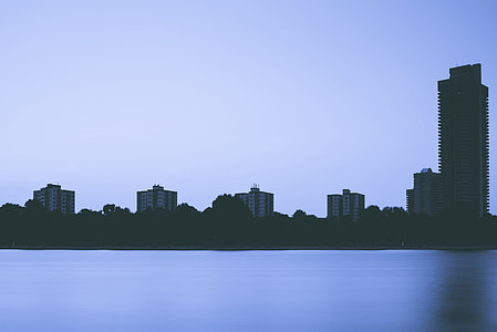 silhouette photo of high rise building near body of water