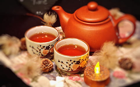 orange teapot and two white ceramic teacups