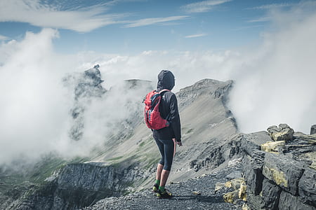 person standing on mountain filled with clouds at day time