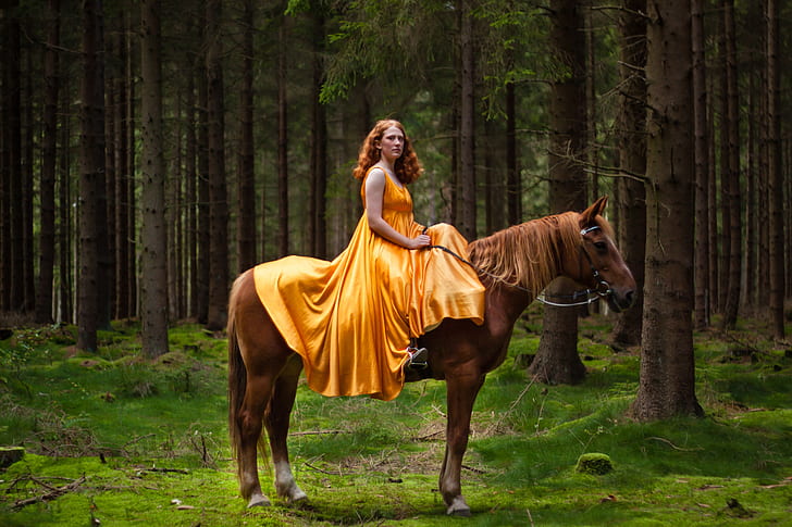 woman riding on brown horse in the middle of the forest