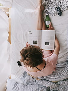 Woman in Pink Dress Sitting on Bed While Reading
