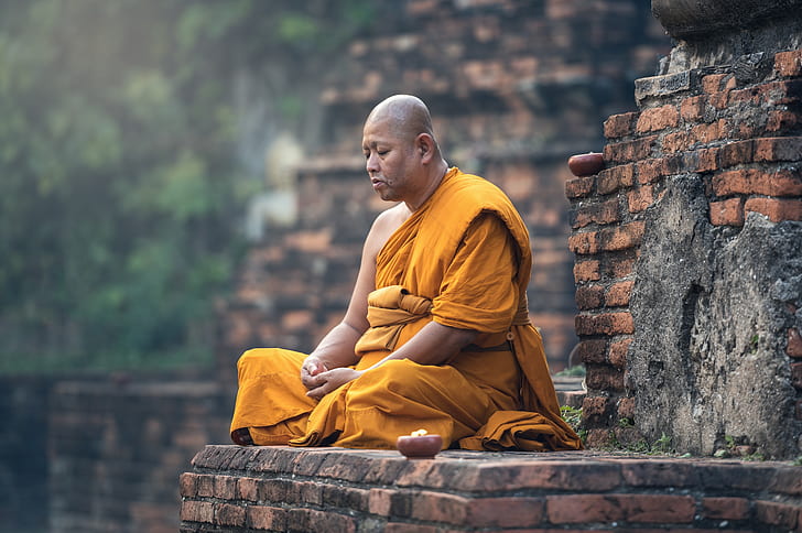 meditating monk on brown brick wall