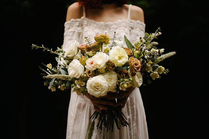 photo of woman holding bouquet of white petaled flowers