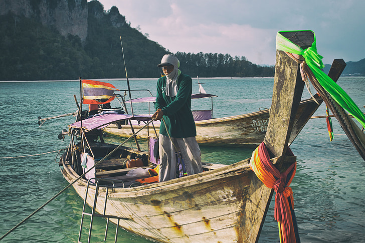Shot of a longtail boat and man. Image captured on Tup Island, Krabi, Thailand