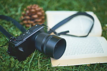 photo of black DSLR camera and white notebook on green grass