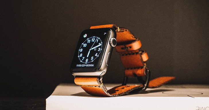 Apple Watch with brown strap on white surface