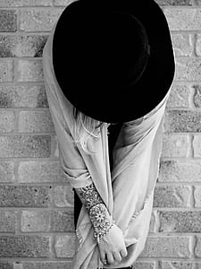 woman in scarf and black cap against brick wall