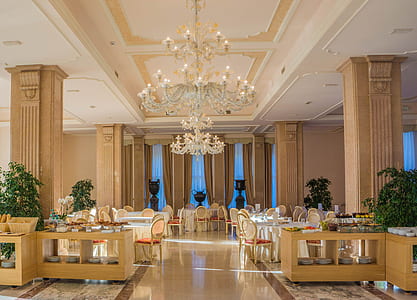 empty chairs and table arrangement and uplight chandelier building interior