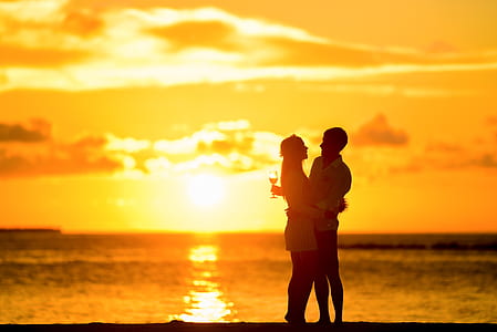 silhouette of man and woman poses at golden hour