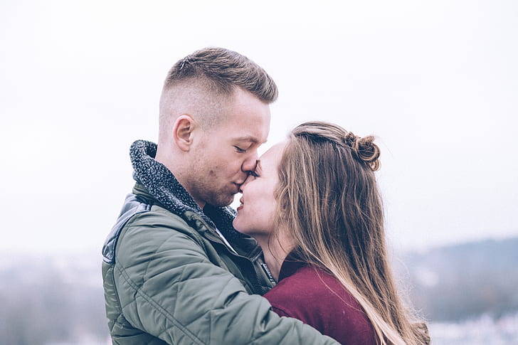 man wearing green jacket kiss her wife on nose photography