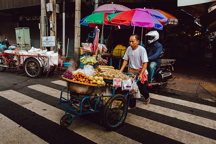 photo of man pushing cart with full of vegetables
