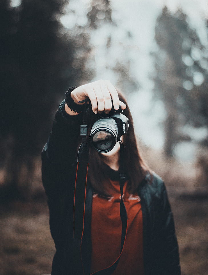 woman in red top holding DSLR camera