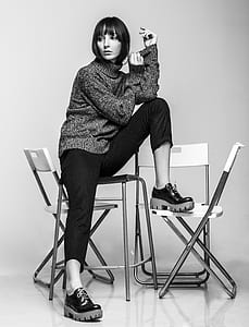 grayscale photo of woman sitting on chairs