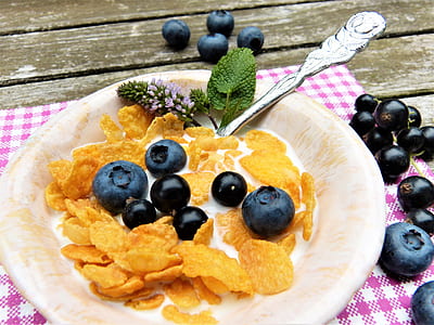 corn flakes with black berries and cream on plate placed on table