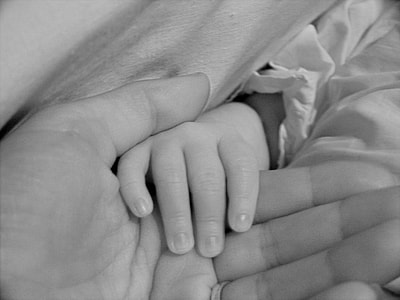 gray scale photography baby holding person's hand