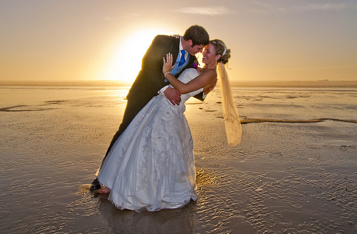 man and woman wearing wedding dresses standing on body of water