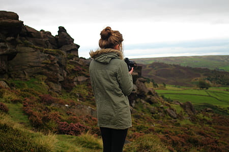 woman wearing green coat standing near mountain
