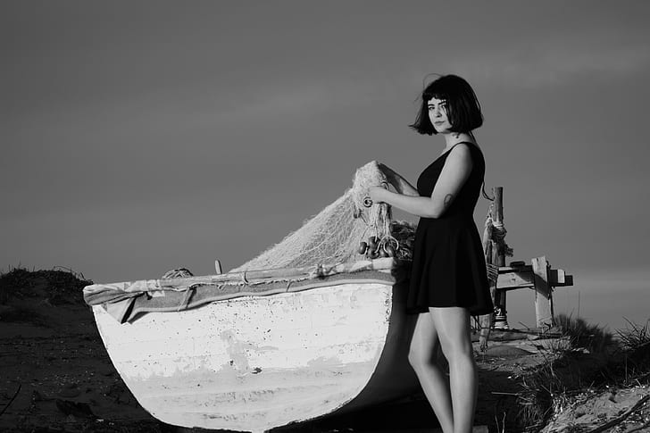 grayscale photo of woman beside boat