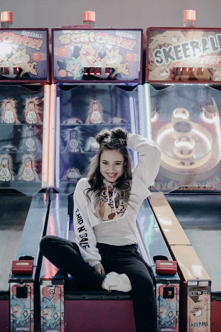 photo of girl in white sweatshirt sitting on arcade game