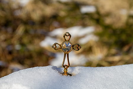 gold-colored cross pendant close up photo