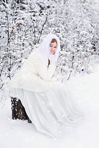 woman sitting on a tree trunk in a snowfield