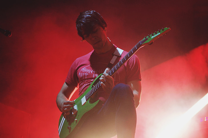 A man playing a guitar on-stage at a music concert