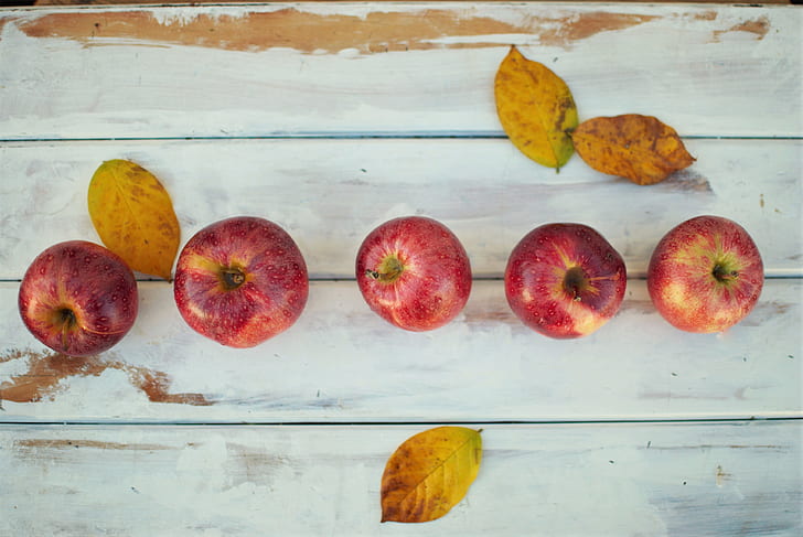 five red apple fruits on white wood pallet
