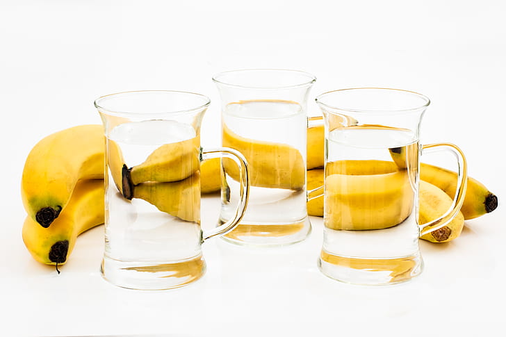 three clear drinking glasses and yellow bananas