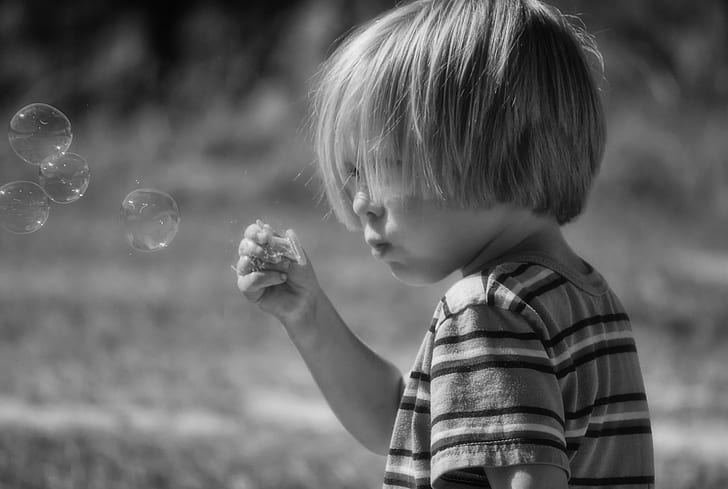 grayscale photograph of toddler blowing bobbles