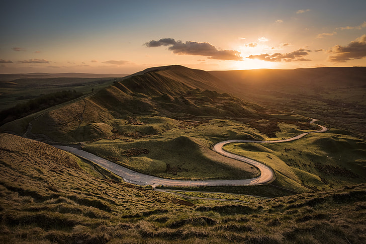 landscape photography of road between hills during golden hour