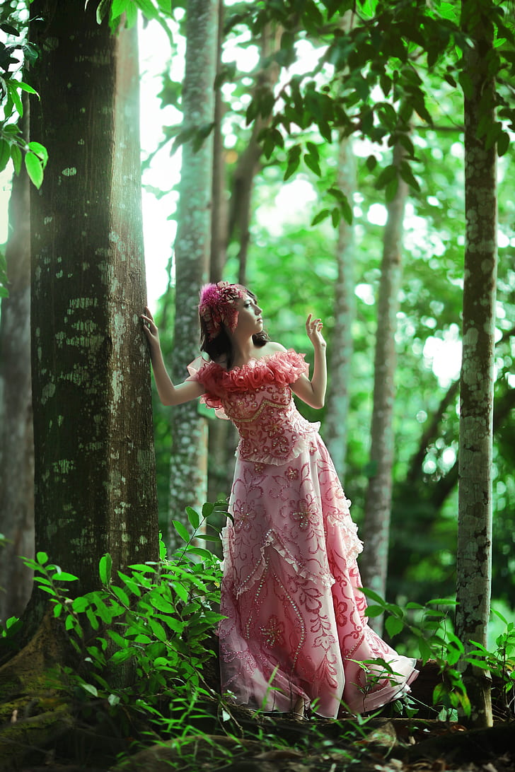 woman wearing pink and red floral off-shoulder dress standing near tree