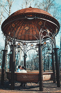 man and woman kissing bandstand during daytime