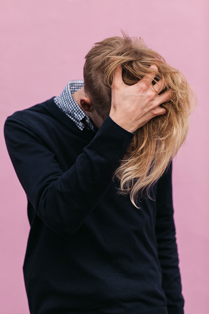 blonde hair man wearing black sweater scratching he's head during daytime