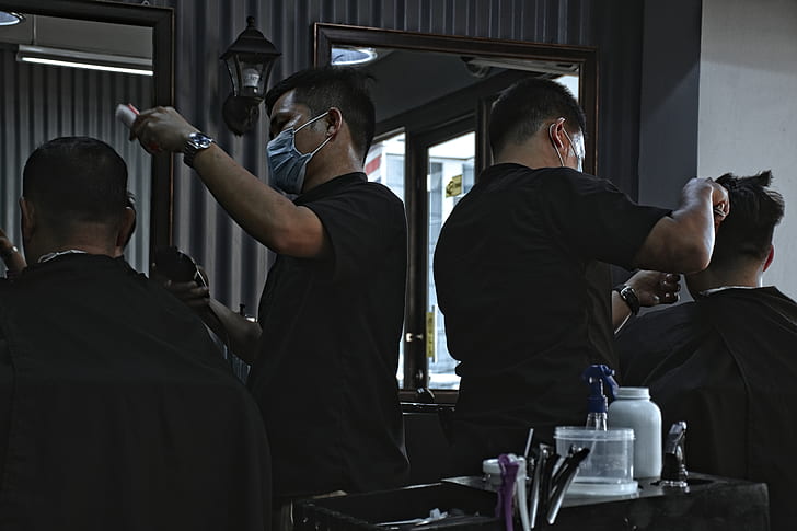 two man in black shirt doing haircut during daytime