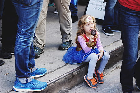 girl wearing wonder woman costume holding ice pop